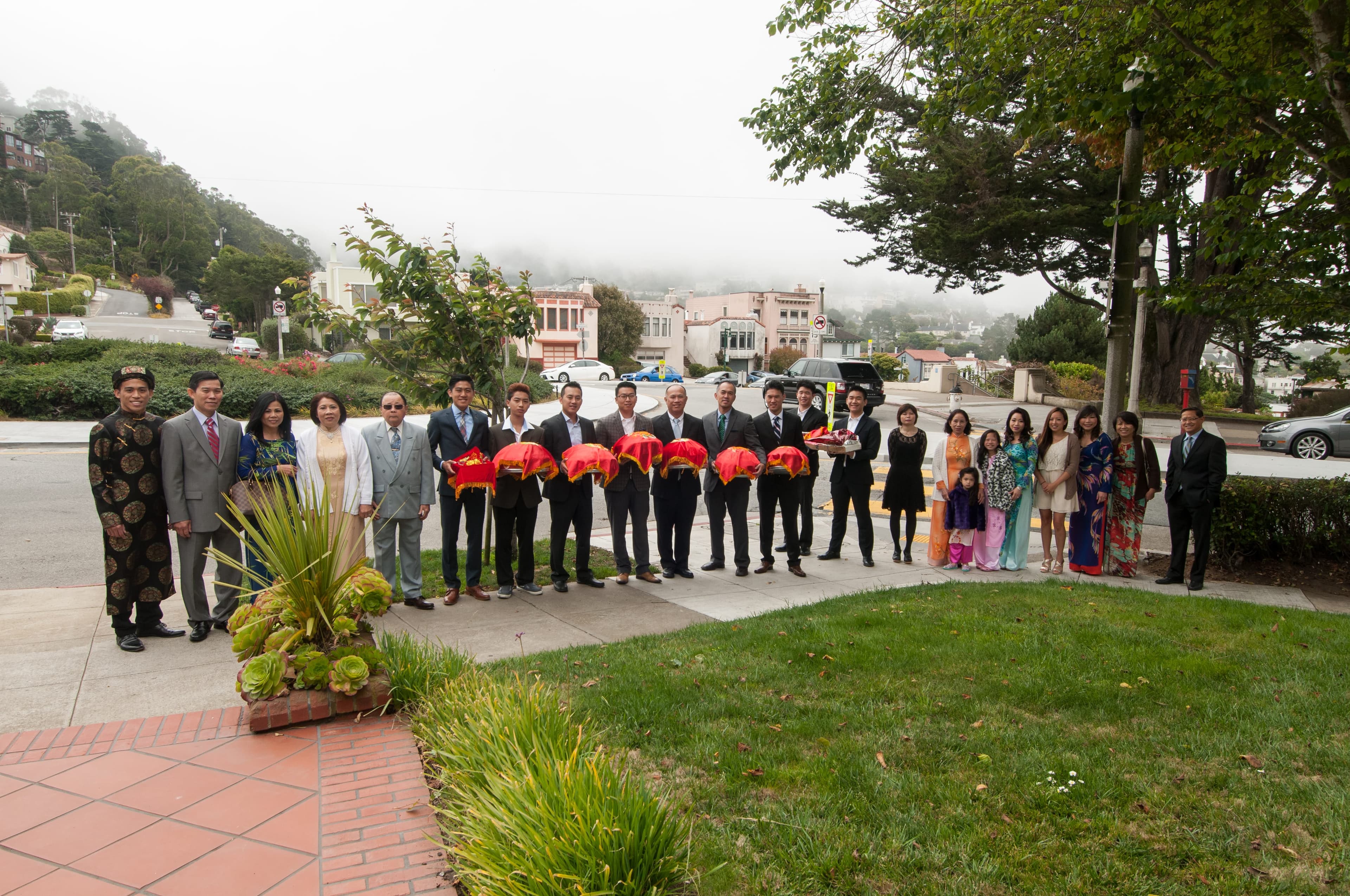 The groom's entourage lined up on the sidewalk holding red mâm quả trays