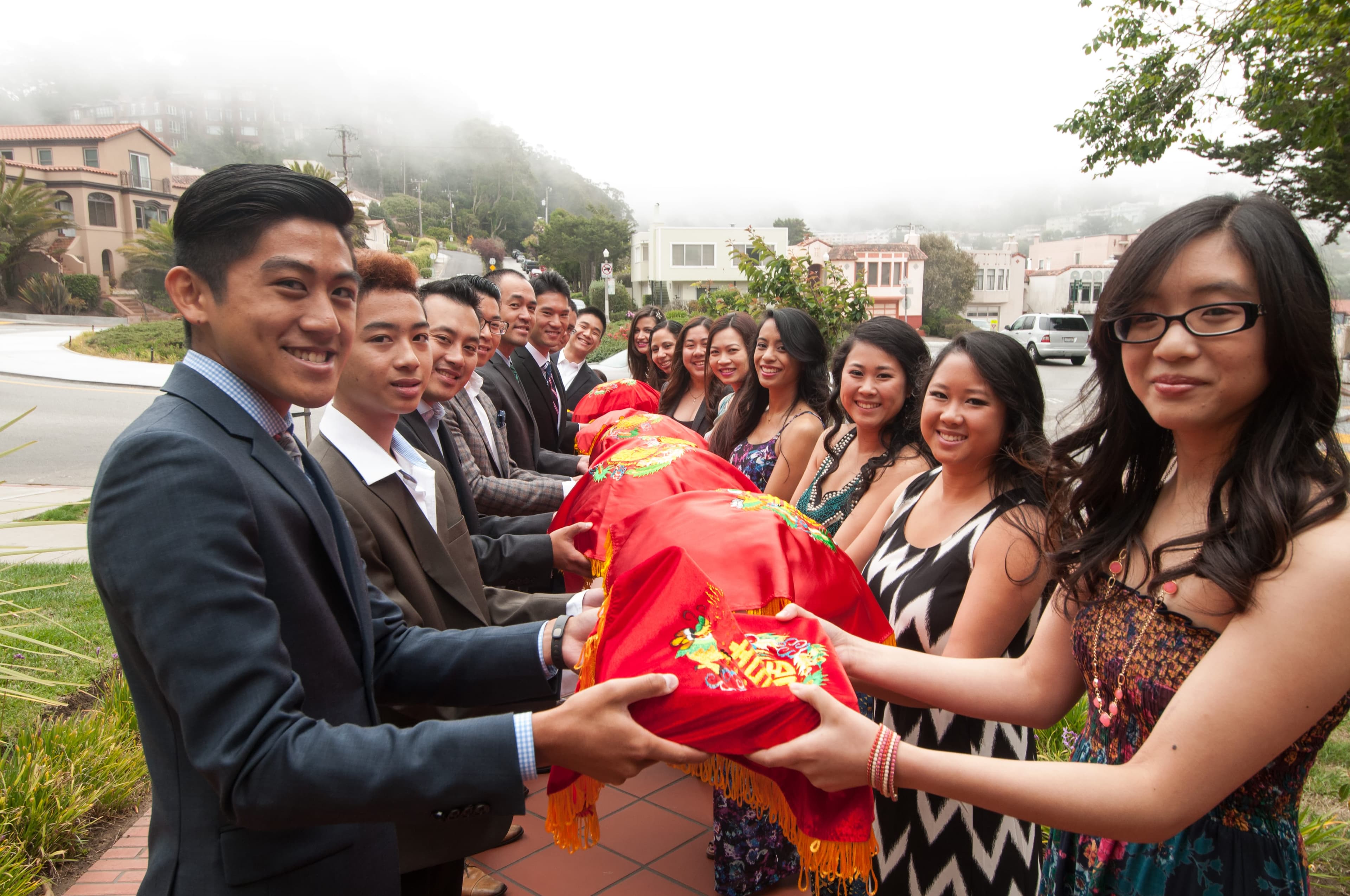The groom's family handing red gift trays to the bridesmaids lined up outside